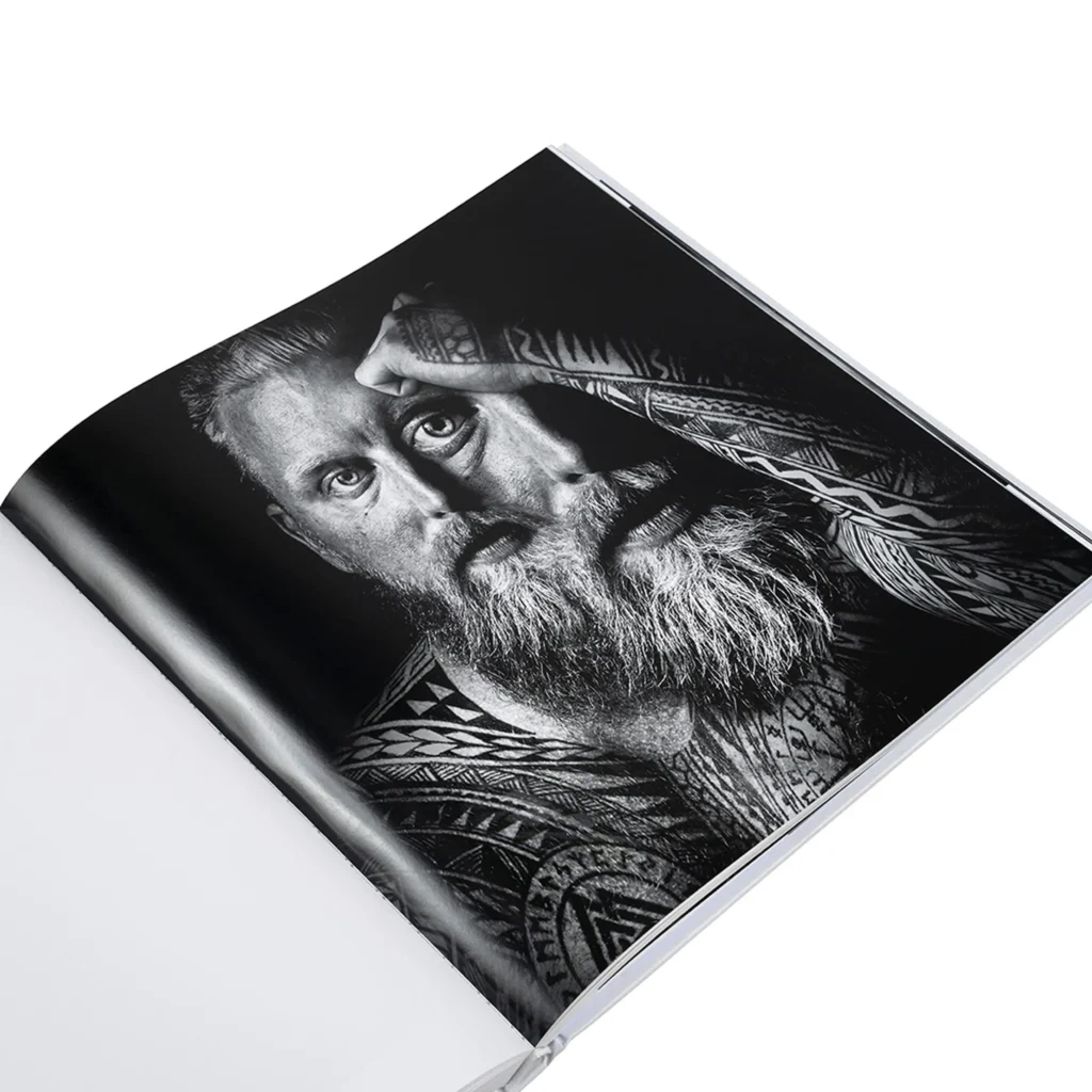 Openliggend fotoboek met zwart-wit portret van een man met tatoeages en baard in goede resolutie.